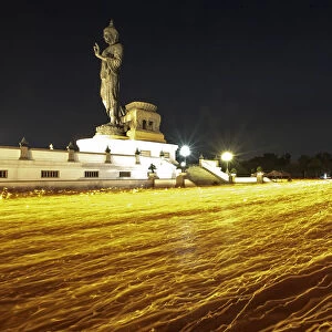 Buddhists holding candles encircle a large Buddha statue during Makha Bucha Day at
