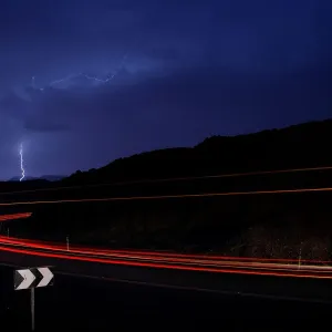 Cars drive as lightning strikes near the site where a group of Israeli youths was swept