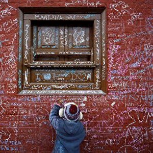 A child writes with chalk on a wall to celebrate Shreepanchami festival at Saraswati