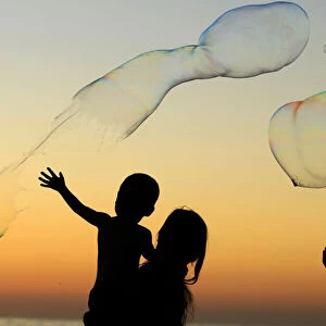 Children play with giant bubbles as the sun sets at Moonlight Beach in Encinitas