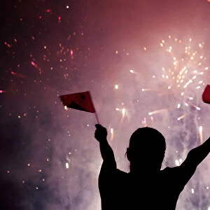 A Chinese girl waves national flags as she watches fireworks at the celebration of