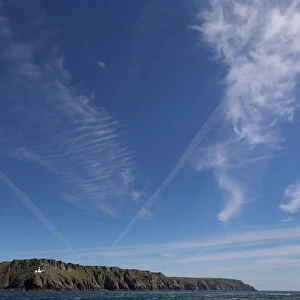 Cirrus clouds and contrails are seen above the island of Lundy and its North Light