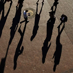 Commuters cast their shadows as they arrive at the Central Business District during