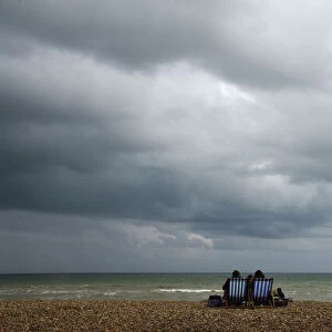 A couple sit on an almost deserted beach at Brighton in south east England