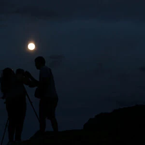 A couple takes a picture of the supermoon rising over Ischigualasto Provincial Park in San Juan