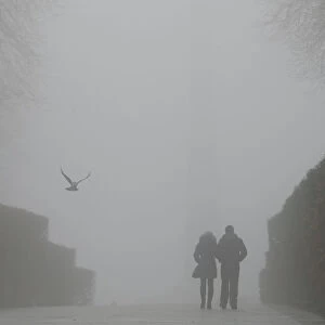 A couple walks in a park on a foggy winter day in central Kiev