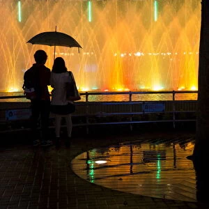 A couple watch an illuminated fountain display in Tokyo