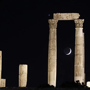The crescent moon and planet Venus appear behind Roman pillars of the Temple of Hercules