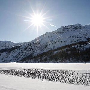 Cross country skiers race over the frozen lake Sils during the Engadin Ski Marathon
