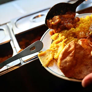 A customer self-serves a plate of food inside the Indian Veg vegetarian restaurant