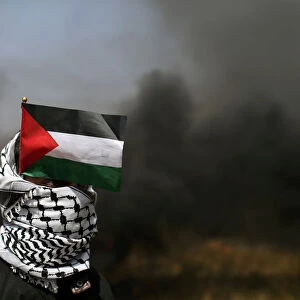 Demonstrator with a Palestinian flag looks on during clashes with Israeli troops at the