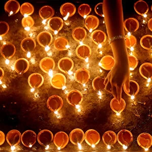 A devotee lights oil lamps at a religious ceremony during the Diwali or Deepavali