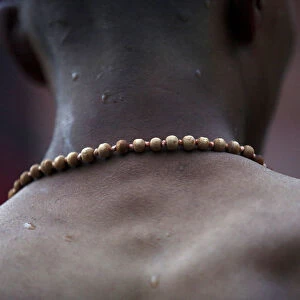 A devotee wearing prayer beads returns after taking a holy bath at the Saali River on the