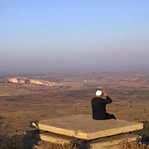 A Druze man uses binoculars as he looks towards Syria from part of an abandoned military