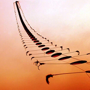 AN ELDERLY CHINESE MAN FLIES A KITE IN THE SHAPE OF A CENTIPEDE AT SUNSET IN WUHAN