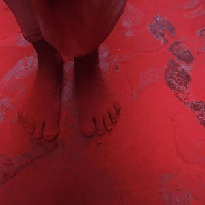 The feet of a man covered in red coloured powder are pictured during Holi celebrations