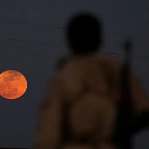 A fighter from Free Syrian Army is seen watching a full moon rises in Daraa