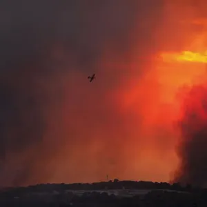 A fire-fighting plane flies over a forest fire that broke out in the north of Israel