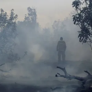 A firefighter tries to extinguish fire on the Israeli side of the border fence between