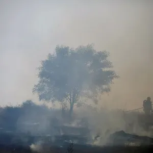 Firefighters try to extinguish fire on the Israeli side of the border fence between