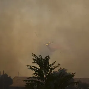 A firefighting plane drops fire retardant during a forest fire in Even Sapir