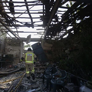 A fireman walks through a destroyed house after an explosion in a fireworks storage