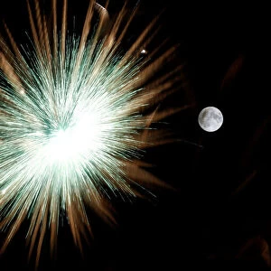 Fireworks explode in front of the full moon during celebrations marking the feast