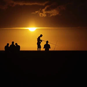 Fishermen stand on Havanas seafront boulevard El Malecon as the sun sets