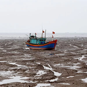 A fishing boat is seen during the low tide at the beach in Thanh Hoa province