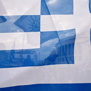 A flag depicting Vergina sun is seen through a Greek flag during a demonstration against