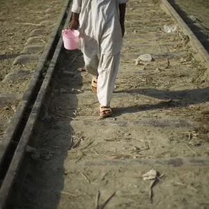Flood victim carries a bucket while walking on a railway next to a relief camp in Flood victim carries a bucket while walking on a railway next to a relief camp in
