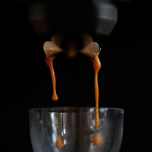 Freshly ground Arabica coffee drips from a domestic coffee machine to make an espresso
