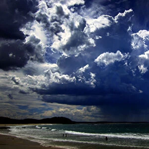 A giant storm cloud can be seen in the sky above swimmers near Mollymook Beach, south