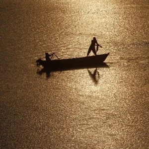 Girls are silhouetted against the rising sun as they fish in the waters of the Ganges Girls are silhouetted against the rising sun as they fish in the waters of the Ganges