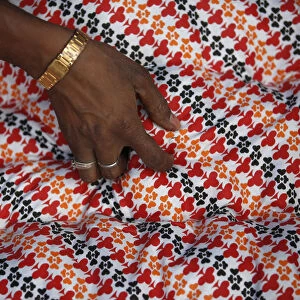 A hand of a migrant worker from India is pictured as he makes a blanket from recycled