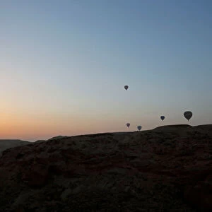 Hot-air balloons carrying tourists fly at sunrise over the city of Luxor
