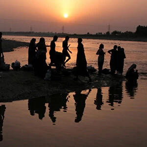 Indian labourers take a bath in the river Tawi in Jammu