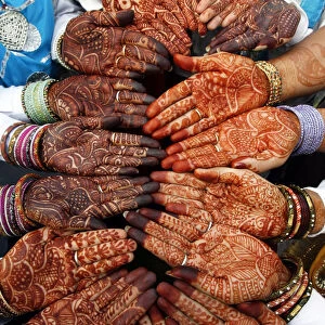Indian women folk dancers show their hands decorated with henna paste before their