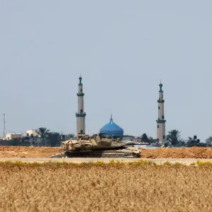 An Israeli tank is seen on the Israeli side of the border fence between Israel