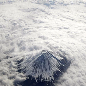 Japans Mount Fuji, covered with snow and surrounded by cloud, is seen from an airplane