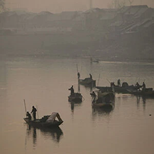 Kashmiri boatmen extract sand from the Jhelum river on a cold winter morning in Srinagar