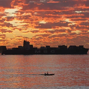 Kayakers take in the last of the days light as they paddle past a ship anchored off