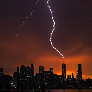 Lightning strikes One World Trade Center in Manhattan as the sun sets behind the city