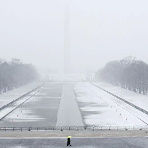 A lone tourist walks on the National Mall near the Lincoln Memorial during a snow storm