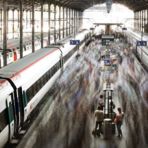 A long exposure picture shows commuters walking on a platform after leaving a train