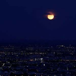 A long time exposure shows the moon over the city of Vienna