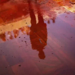 Man casts a reflection on the floor covered with red coloured water during Huranga Man casts a reflection on the floor covered with red coloured water during Huranga