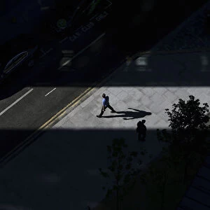A man casts a shadow as he walks through a shaft of sunlight in London