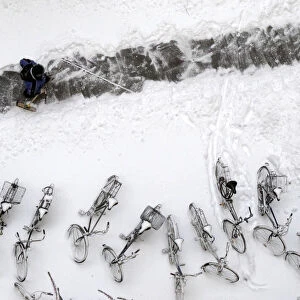 A man clears snow to form a path in a yard during in Berlin