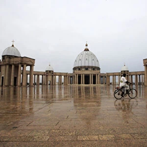 A man cycles past in front of the Basilica of Our Lady of Peace of Yamoussokro, a